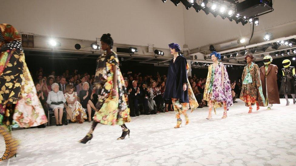 The Queen and Anna Wintour watch as a models walk the runway