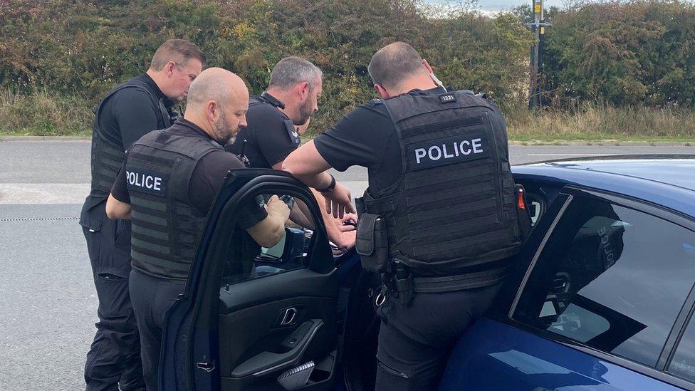 Police officers putting someone in an unmarked car