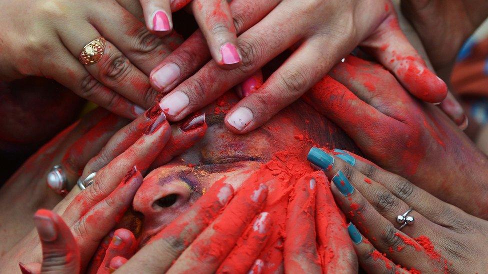 Hands covering face in coloured powder