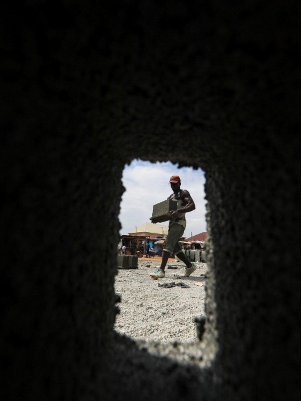 A man carries a moulded block.