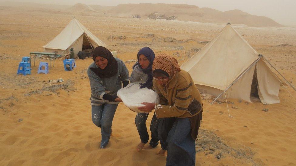 Students carry rock from the dig