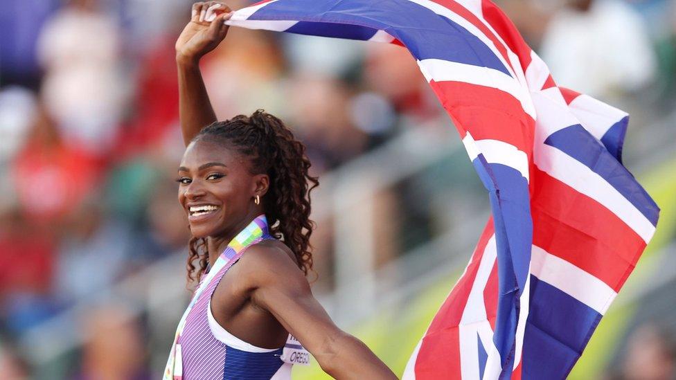 dina asher-smith following her 200m sprint finish holding the uk's flag