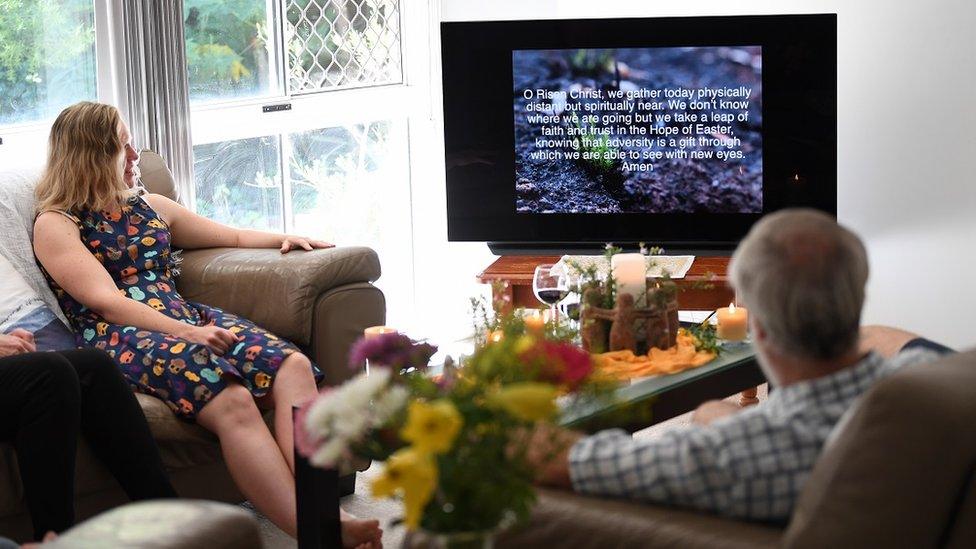 Darryl Nelson (R) and his daughter Monique (L) watch a liturgy sent to them by their church community as they celebrate Easter in their home in Brisbane, Australia