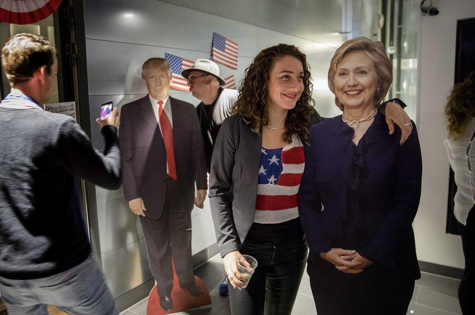 Visitors take a selfie with portraits of presidential candidates Hillary Clinton and Donald Trum