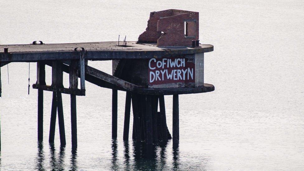 A sign reading 'Cofiwch Dryweryn' (meaning 'Remember Tryweryn') at the end of a jetty in Milford Haven