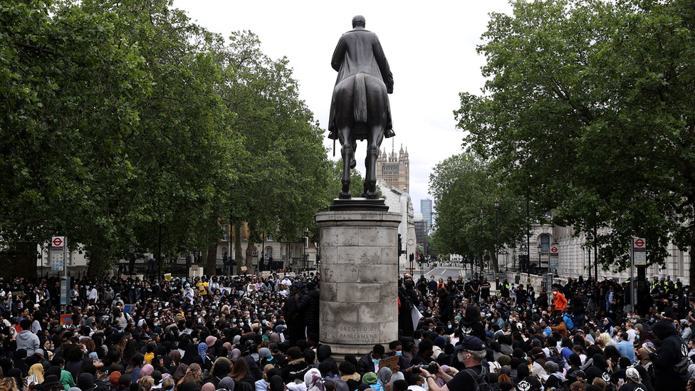 Demonstrators in London walk past statue