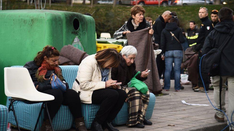 People rest at a gathering point outside the historic center of Norcia on October 30, 2016 after a 6.6 magnitude earthquake hit central Italy early in the morning today.