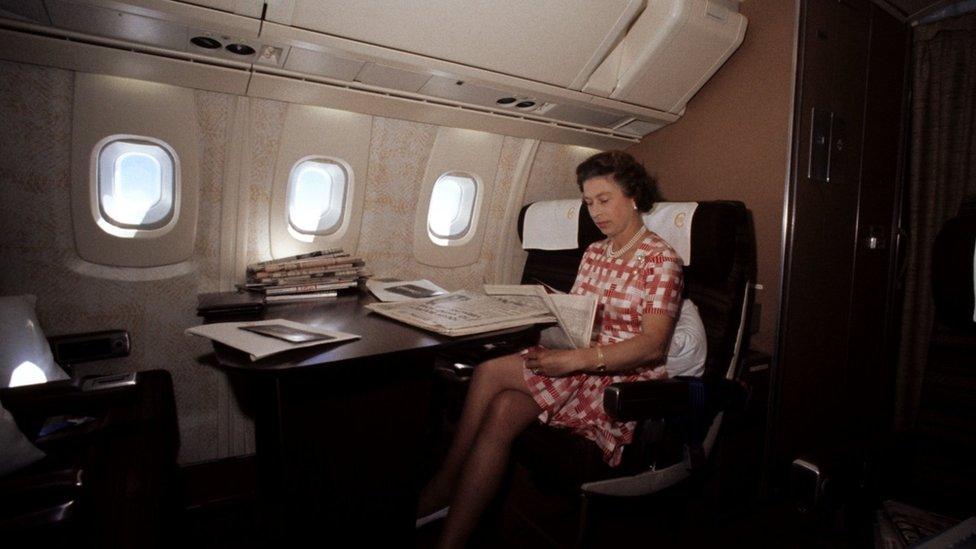 Queen Elizabeth II reading on board Concorde.