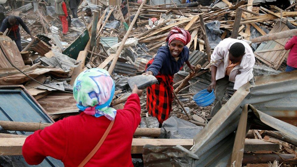 Catharine Kamiri (L) and her sister Mercy Wanjiku (C) collect the remainings of their belongings after bulldozers demolished their house to make way for a new road in the Kibera slum in Nairobi,