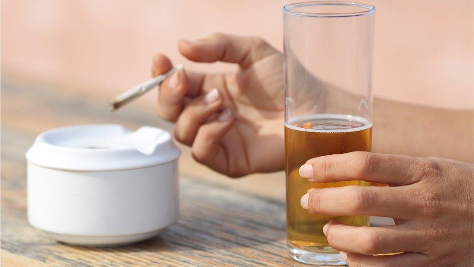 Hands holding a cigarette and drinking alcohol