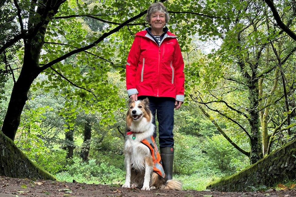 A woman stands next to a dog