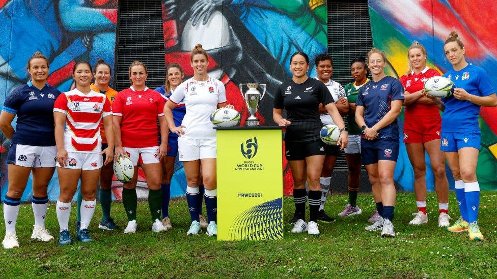 the twelve captains stand together next to the world cup trophy