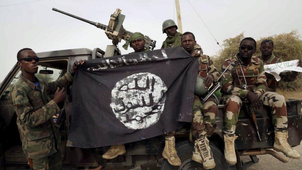 Nigerian soldiers holding up a Boko Haram flag captured in 2015