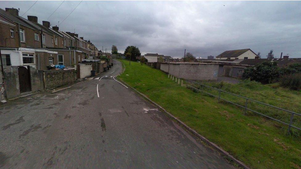 The garage, pictured before the artwork appeared, is behind a row of houses with the steelworks in the background