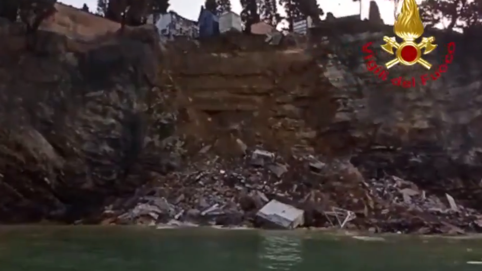 Photos of the collapsed cliff show coffins and debris in the water