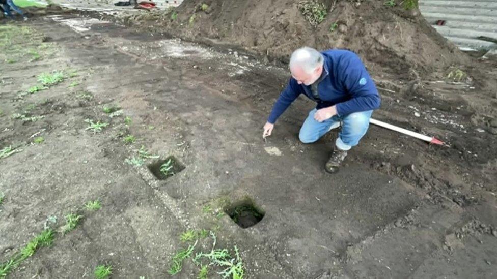 Archaeologist points at ground