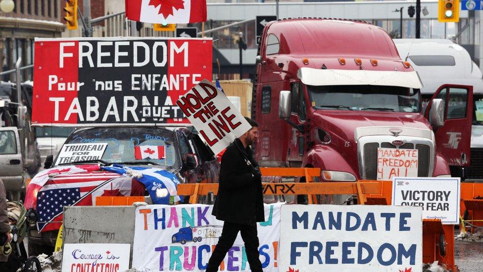 A protester walks in front of parked trucks as demonstrators continue to protest the vaccine mandates implemented by Prime Minister Justin Trudeau on February 8, 2022 in Ottawa