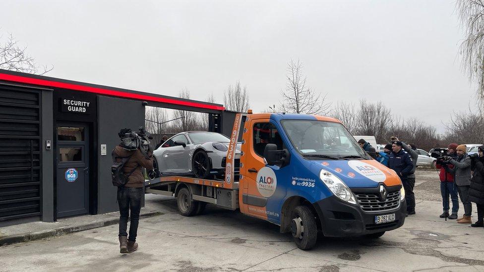 Porsche being taken away on police tow truck at Andrew Tate's compound in Bucharest