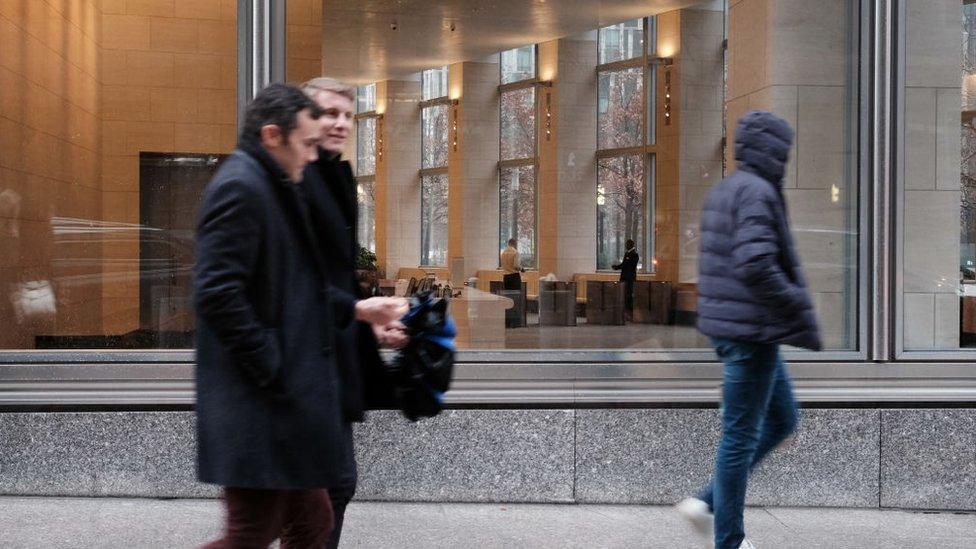 Office workers walk past an office lobby in NY