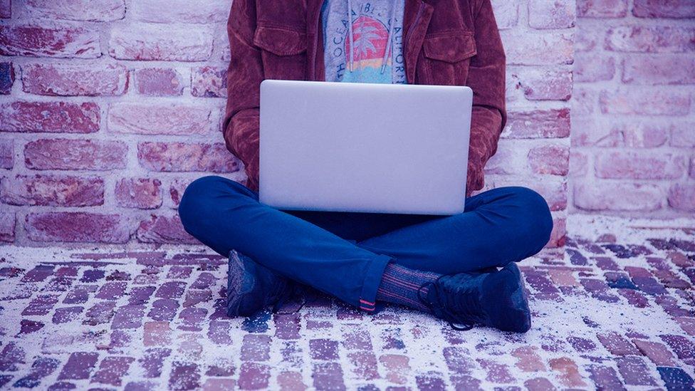 A man sitting looking at a laptop