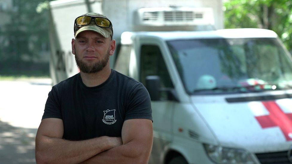 Aleksey Yukov standing next to the white van, marked with a red cross