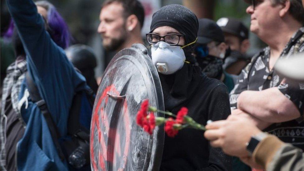 An anti-Trump demonstrator protects herself with a homemade shield during the rally at Chapman Square in downtown Portland (04 June 2017)