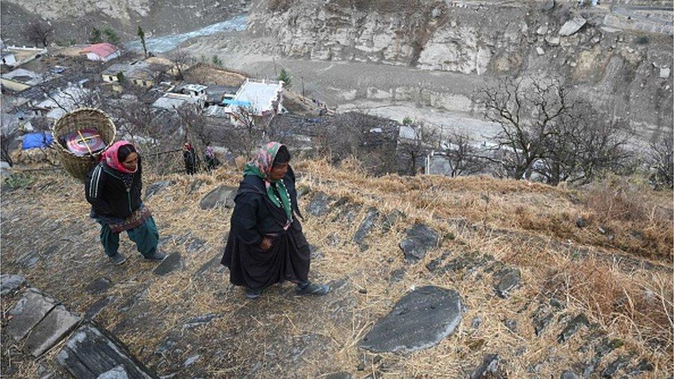 In this picture taken on February 10, 2021, women from Raini Chak Lata village walk along a mountain path in Chamoli district. - L