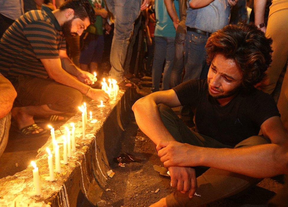 People light candles at the scene of a massive car bomb attack in Karada, Baghdad, 4 July