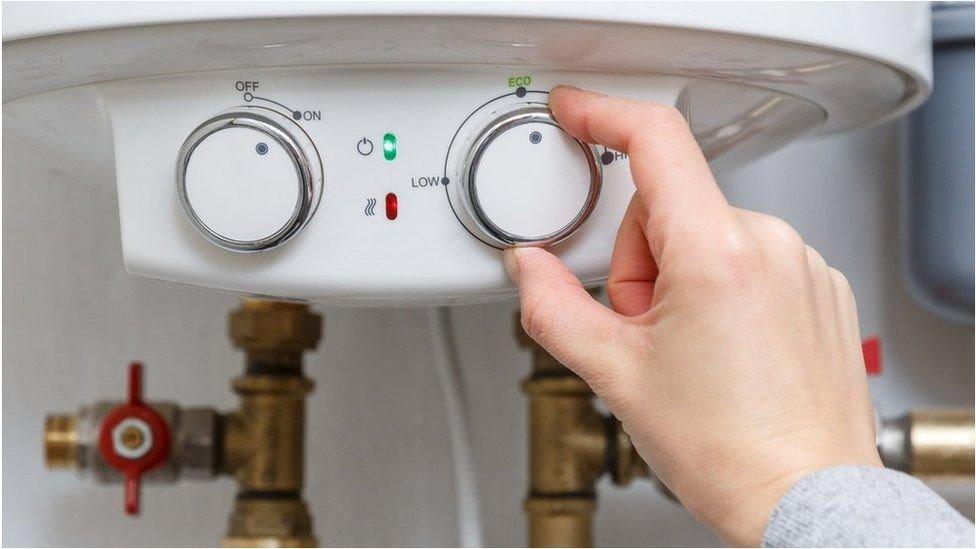 A person turns a control knob on a gas boiler