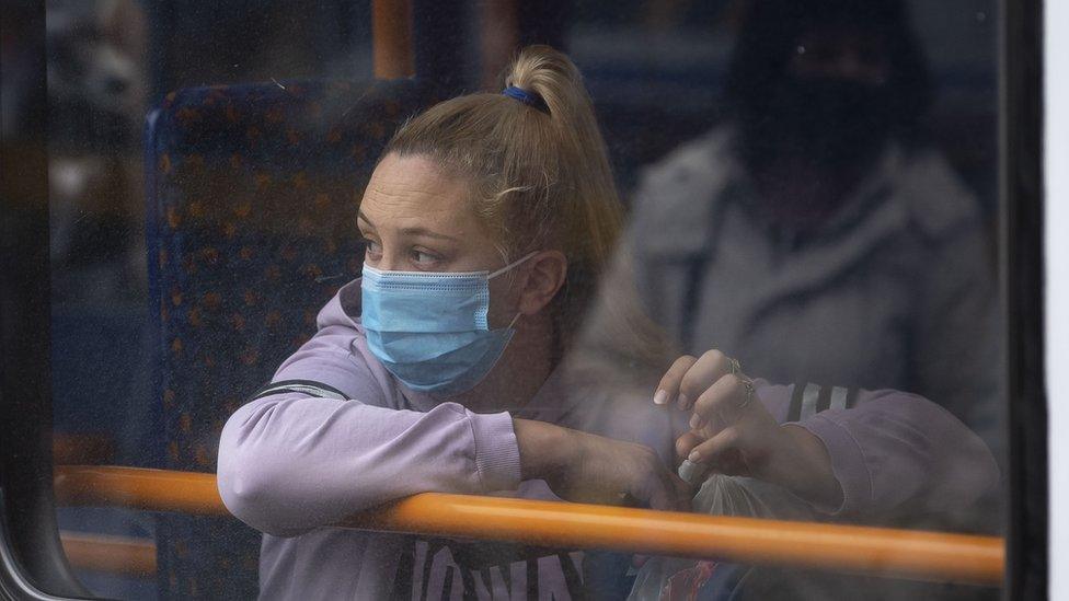 A woman looks out of the window of a bus