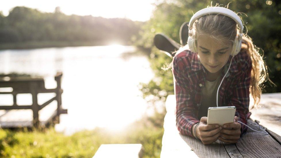 Girl-using-phone-by-the-lake.