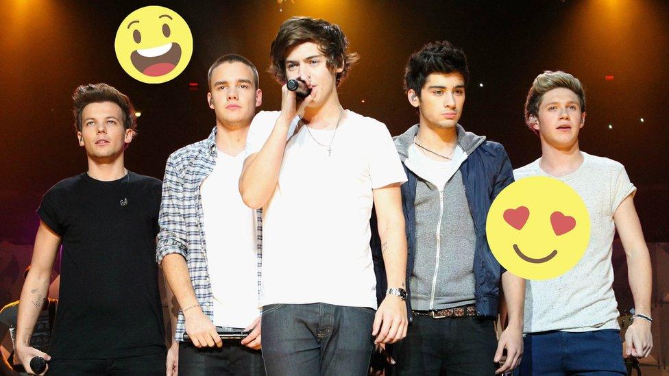 The five members of 1D together on stagem Harry sings into a microphone.