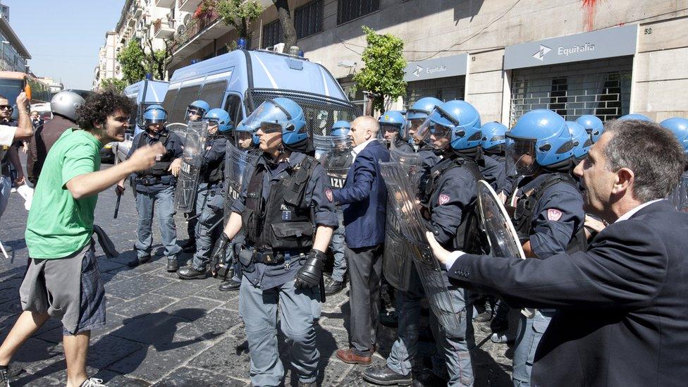 Demonstrators (L) face riot policemen as they try to enter the offices of Equitalia, Italy's tax collection agency during a protest against the government's austerity measures in May 2012