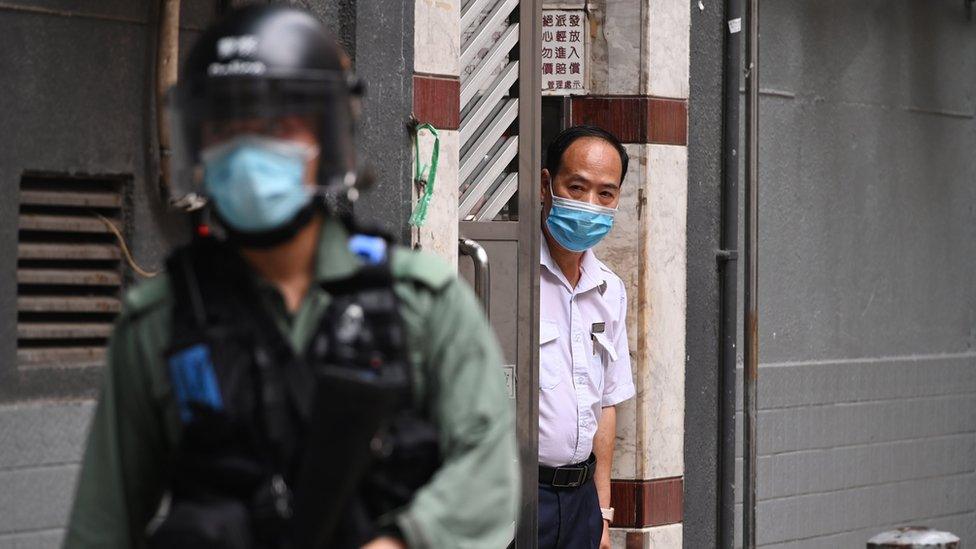 A man looks out from a doorway as a riot police walk past during a rally against a new national security law on the 23rd anniversary of the establishment of the Hong Kong Special Administrative Region in Hong Kong, China