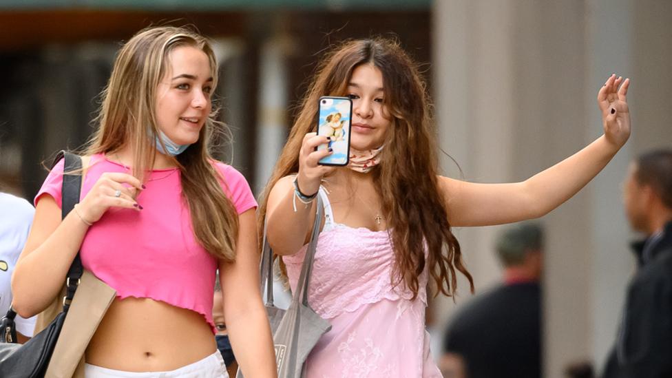 People take a selfie while shopping in SoHo, New York