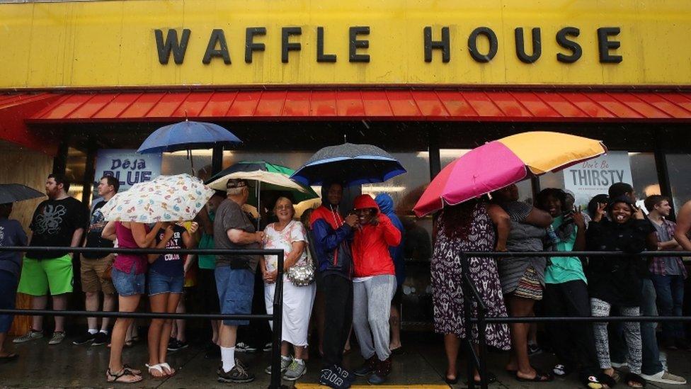 Residents in Wilmington queue holding umbrellas outside a Waffle House