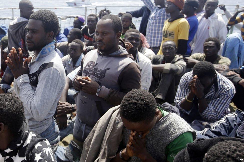 Migrants pray as they arrive aboard the Belgian Navy Vessel Godetia at the Trapani harbor, Sicily, Italy, Wednesday, 24 June 2015