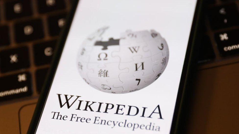 Wikipedia logo displayed on a phone screen and a laptop keyboard