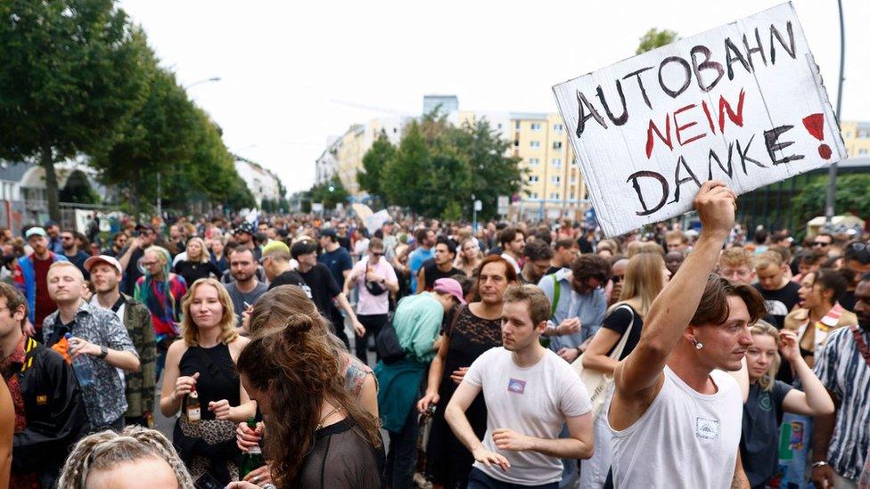 Raver at Berlin dance party holds sign saying no thank you autobahn