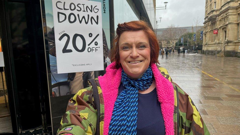 woman standing on the street in from on Howells buildng and a closing sign