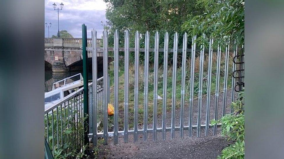 Fenced-off footpath, with bridge in the distance