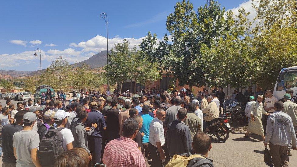 Angry crowds awaiting aid surround a local reporter in Asni