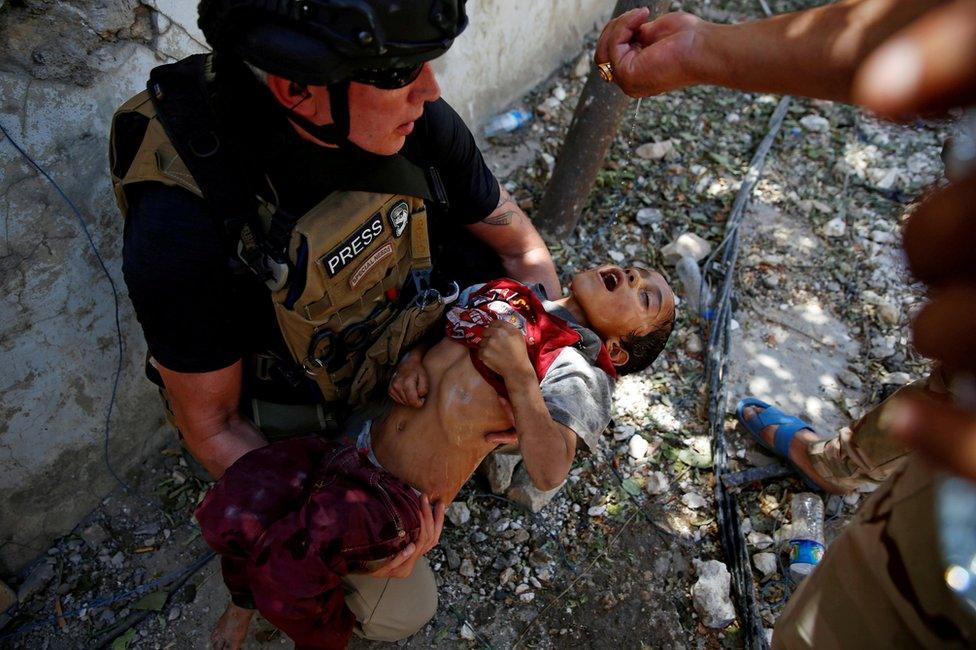 An Iraqi soldier from the 9th Armoured Division gives drops of water to a dehydrated child rescued earlier by soldiers at the frontline in western Mosul (13 June 2017)