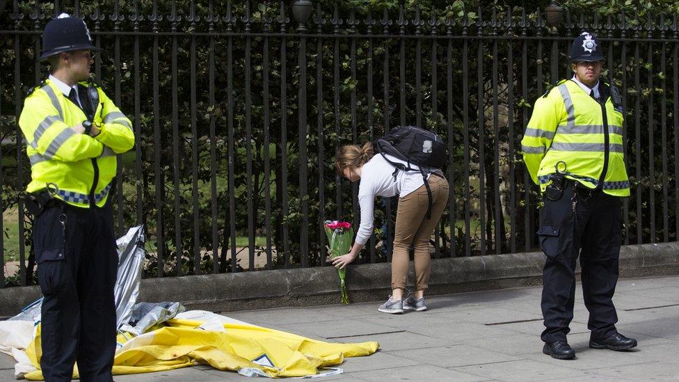 Woman lays flowers at scene of stabbing in Russell Square as police stand guard
