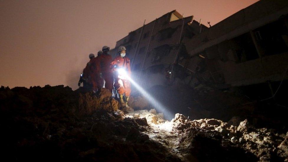 Firefighters use torches to search for survivors among the rubble of collapsed buildings after a landslide hit an industrial park in Shenzhen, Guangdong province, China December 20, 2015. R