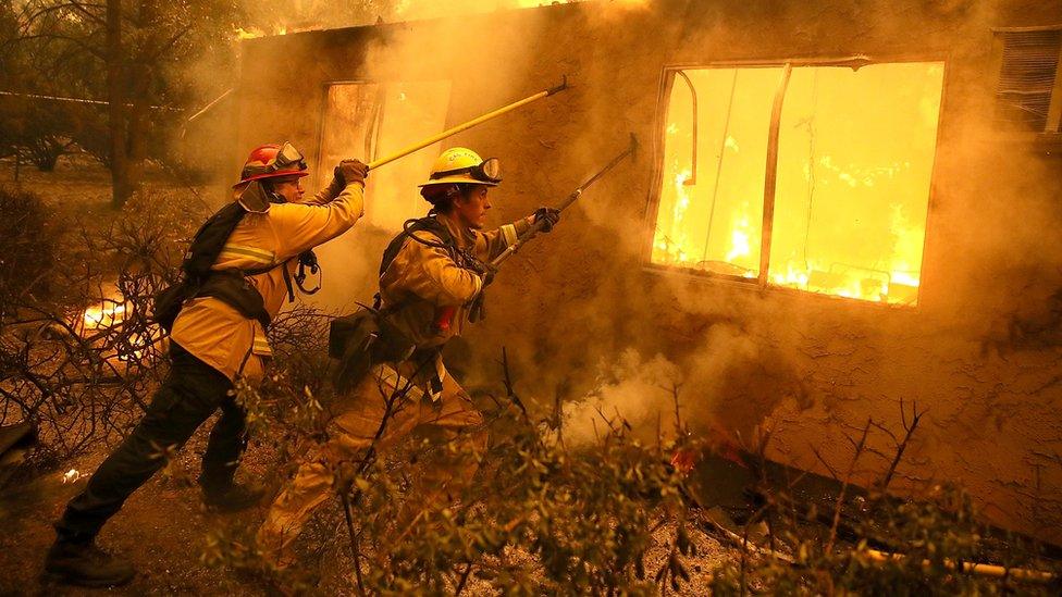 Firefighters try to keep flames from burning home from spreading to a neighbouring apartment complex as they battle the Camp Fire in November 2018