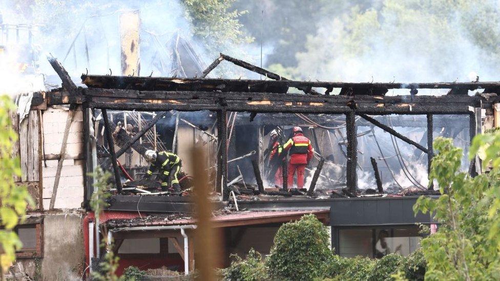 Firefighters inspect the burnt building