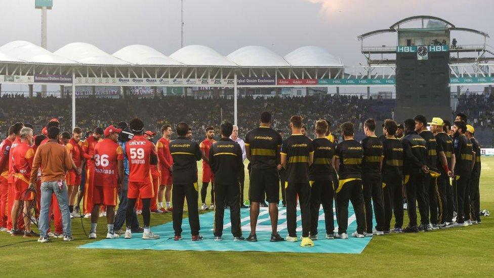 Cricket players stand in a circle for minute's silence