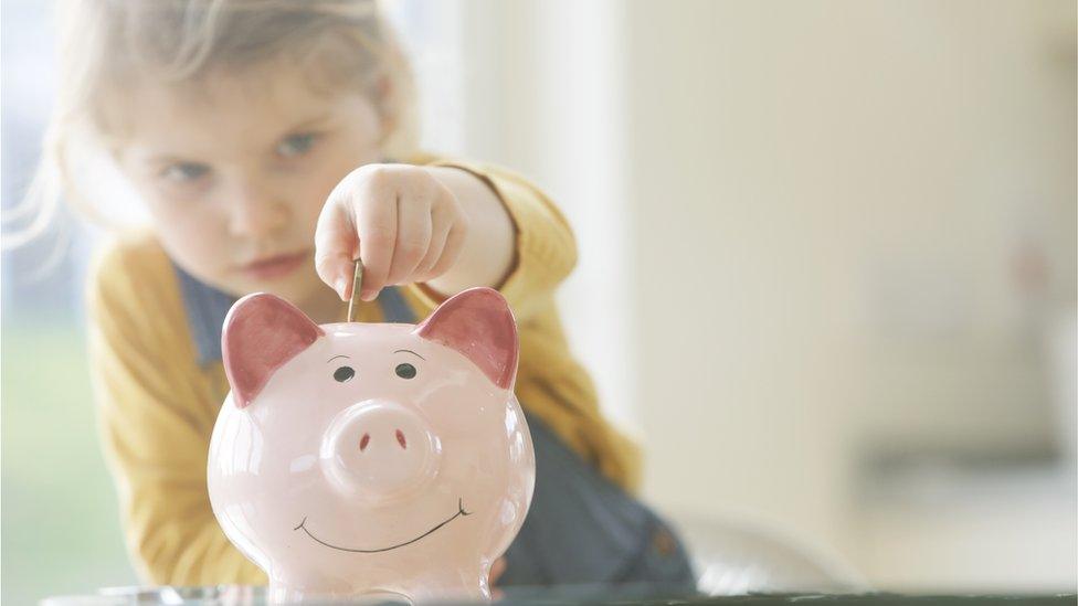 Girl putting money in piggy bank