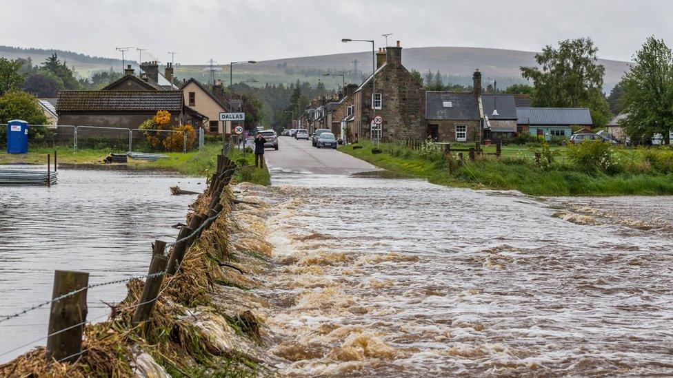 Water rushes over the road out of Dallas in Moray